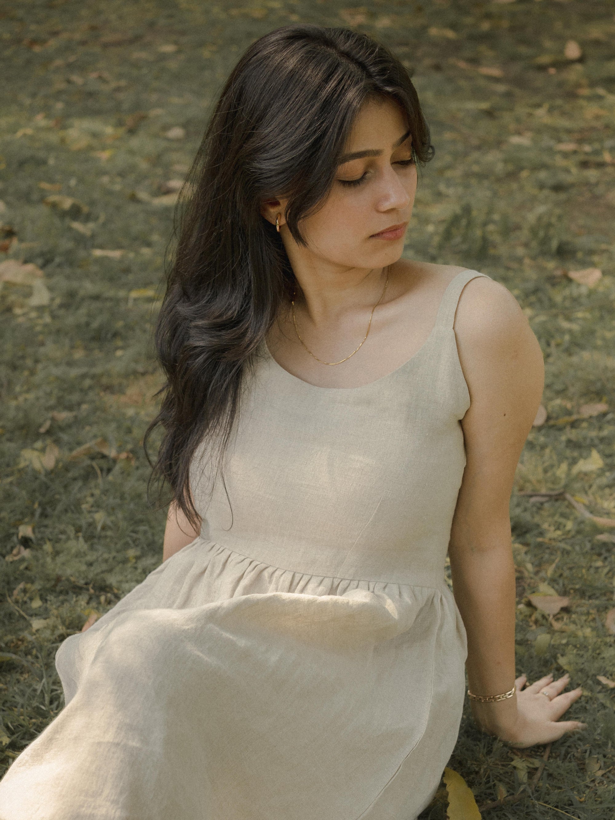 Woman in a light dress sitting on the grass