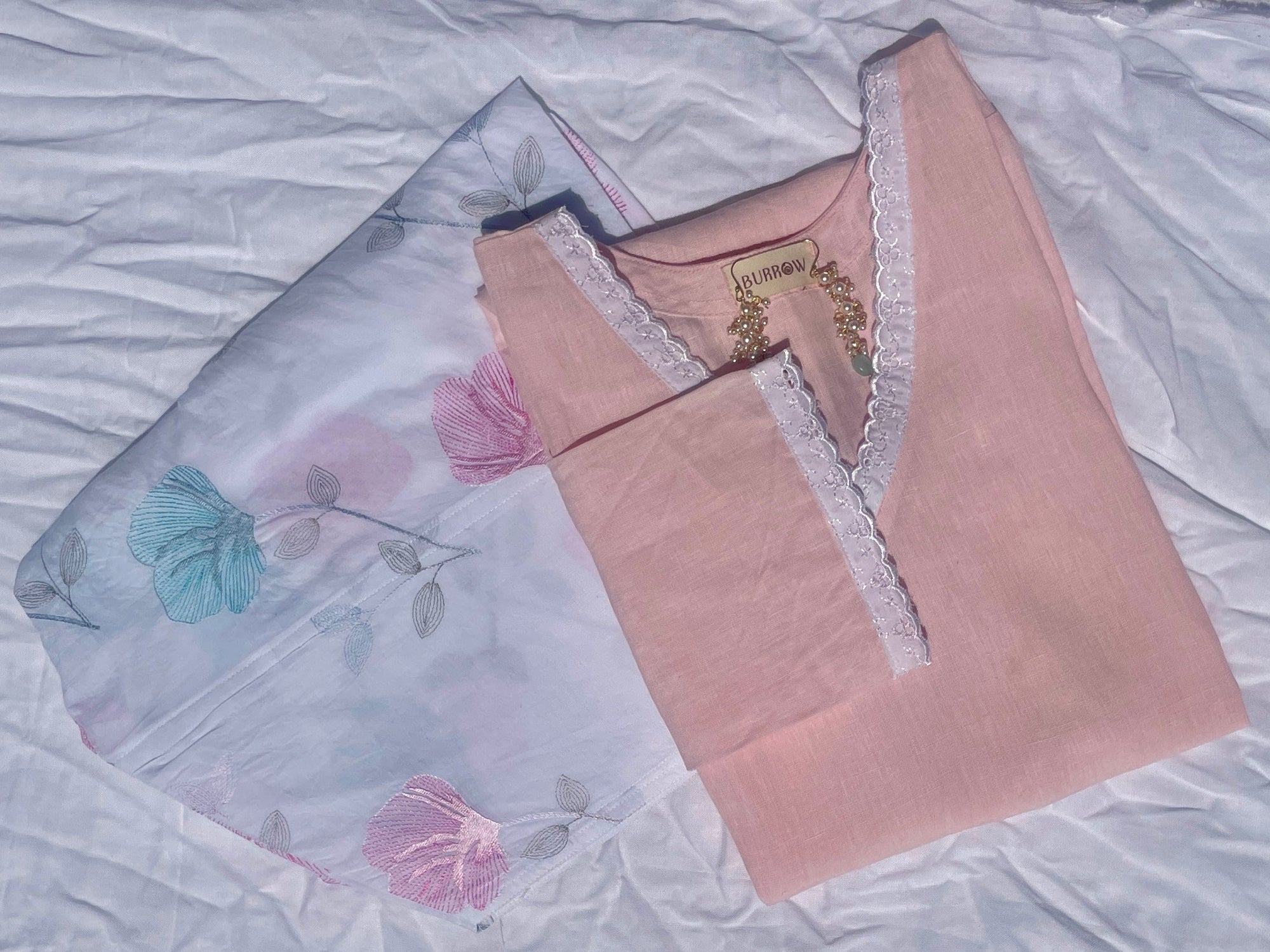 Two pieces of fabric with floral embroidery on a textured surface