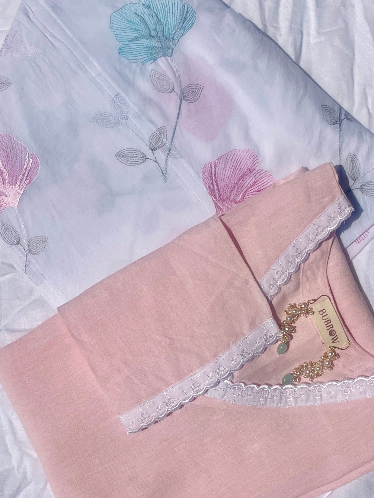 Embroidered fabric with floral designs on a textured white background