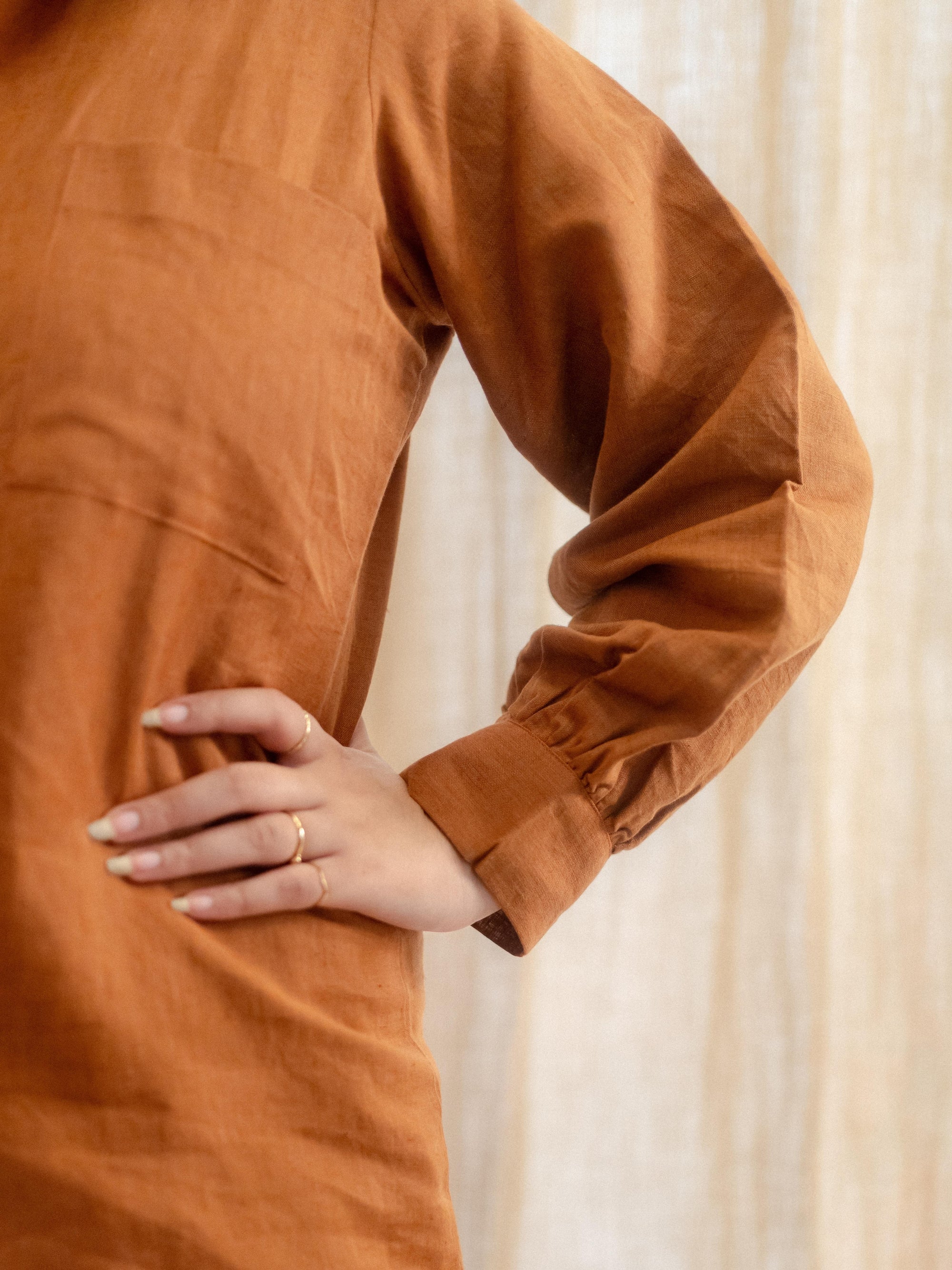 Brown long-sleeve shirt worn by a person with a neutral background